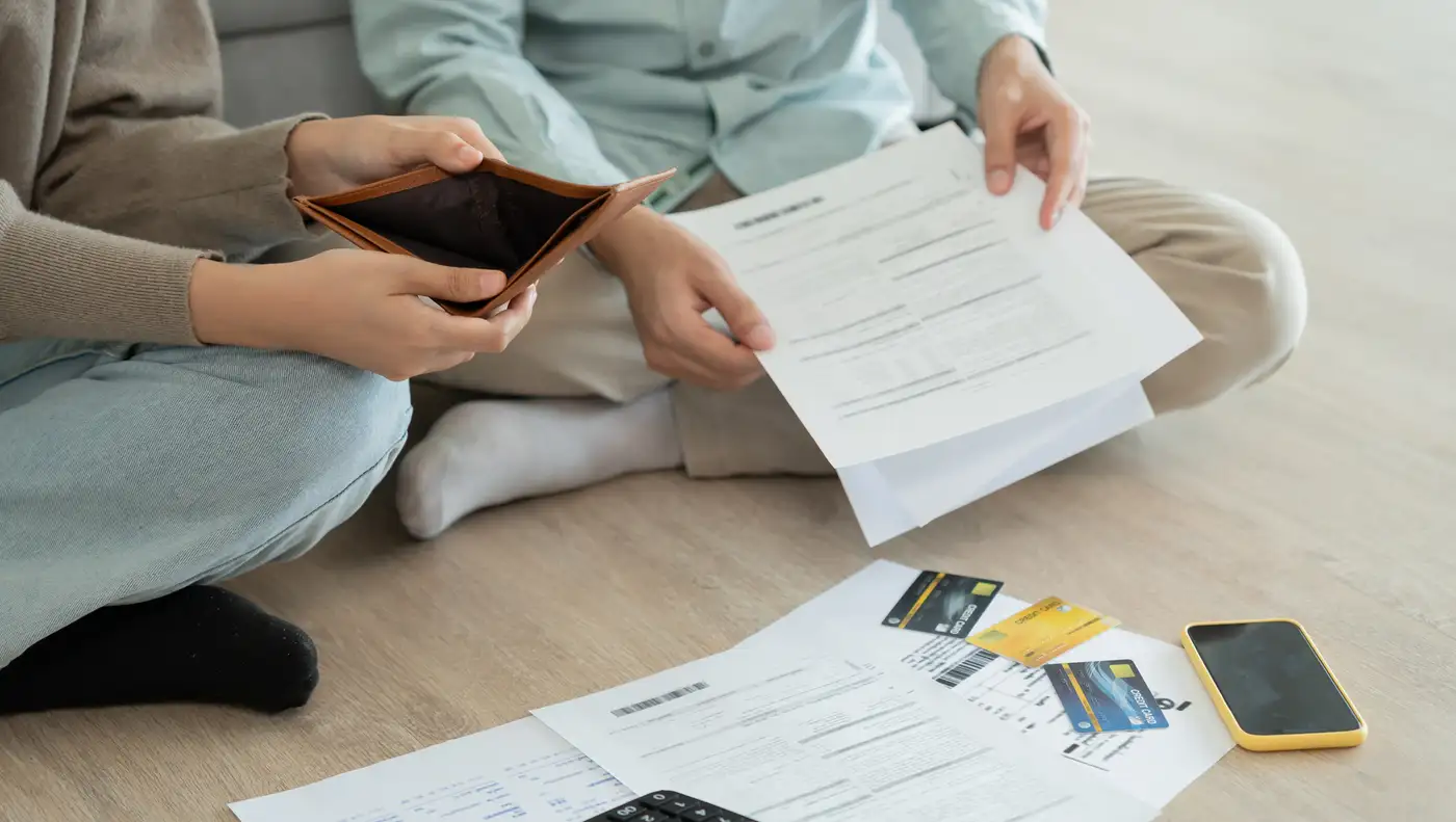 pareja mirando cuentas y mostrando billetera vacía por gastos muy altos