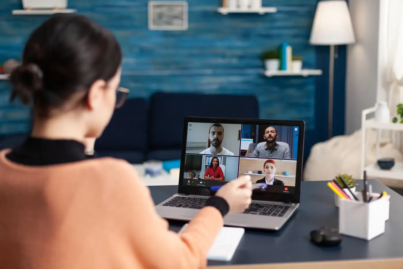 Jóven profesional trabajando remoto en laptop en su casa con cólegas de trabajo